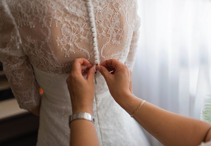 Die Trauzeugin hilft der Braut, das passende Kleid zu finden.